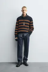 Jersey de punto con ajuste relajado, cuello redondo y manga larga. Presenta un diseño de rayas horizontales en color naranja sobre una base de color azul marino, con acabados en rib en puños, cuello y ruedo.