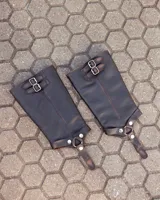 Bota de caña alta confeccionada en cuero color marrón caoba con acabado desgastado. Presenta una suela track robusta, correas con hebillas en la parte superior de la caña y un arnés decorativo con herrajes metálicos en el tobillo.