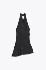 Vestido corto negro con cuello halter que se anuda en la espalda, escote drapeado y frunces laterales. El bajo es asimétrico con un volante.