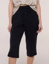 Pantalón capri negro de calce relajado y pierna recta, confeccionado en algodón. Posee cintura elastizada con cordón ajustable, bolsillos delanteros y detalle de presilla con botón en los ruedos.