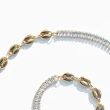 Pulsera dorada con doble diseño: una hilera de cristales claros y una cadena de eslabones originales.