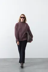 Polera gris de tejido suave de punto, con cuello alto, mangas abullonadas, puños elásticos y diseño relajado.
