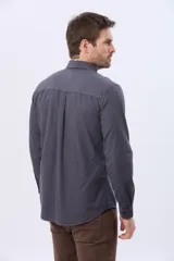 Camisa de manga larga color gris oscuro, con efecto lavado, cuello camisero con botones y cierre frontal abotonado.