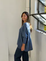 Sweater de punto color azul, con cuello redondo, corte holgado y mangas largas con puños ajustados.
