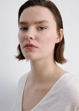 Camiseta de lino color blanco, con cuello en V y mangas cortas, de corte recto y clásico.