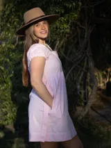 Vestido corto celeste a rayas verticales, con cuello en V, mangas cortas abullonadas, corte a la cintura con frunces y lazo para atar.