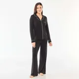 Pijama de dos piezas color negro, compuesto por una camisa de manga larga con cuello solapa, cierre frontal de botones y bolsillo en el pecho, con detalles de vivo en contraste blanco. Incluye pantalón largo a juego.
