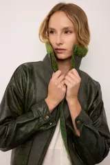 Chaqueta estilo bomber de cuero vacuno en color verde vintage, con cuello y forro interior de corderito al tono. Presenta cierre frontal completo y un diseño de inspiración retro con acabado texturizado.