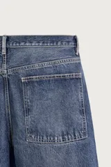 Jeans tapered wide fit de hombre, confeccionados en denim de algodón con efecto lavado en tono azul oscuro. Presentan diseño de cinco bolsillos, tiro medio, corte relajado y cierre frontal con cremallera y botón.