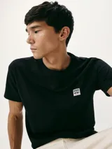 Camiseta de manga corta color negro con cuello redondo y parche con logo de la marca Hering en el pecho.