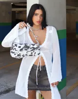 Vestido corto de tejido crochet en color blanco, con mangas largas acampanadas y cierre frontal mediante cordones ajustables. Presenta un diseño calado con terminaciones en ondas.