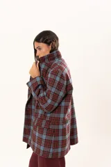 Blazer de corte oversize con estampado de cuadros en tonos azul, bordó y marrón. Presenta solapas clásicas, bolsillos con solapa en el frente y cierre frontal con botones.