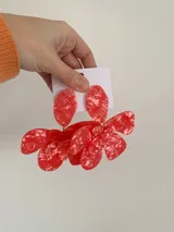 Aros colgantes de gran tamaño con diseño de flor, realizados en resina roja con efecto marmolado.