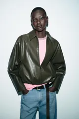 Chaqueta estilo bomber de efecto piel en color verde oliva, con cuello solapa, cierre frontal con cremallera, mangas largas y bajo elástico.