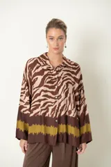 Camisa italiana de manga larga con estampado de cebra en tonos marrón y beige, con una guarda esfumada en tonos marrón oscuro y verde oliva en el bajo. Tiene un calce holgado y cierre frontal con botones.