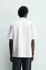 Camisa azul marino de corte regular fit confeccionada en tejido fluido de algodón y lino, con cuello solapa, manga corta, bolsillo aplicado en el pecho y cierre frontal con botones.