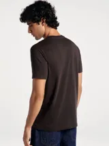 Camiseta blanca de algodón con cuello redondo y mangas cortas. Estampa rectangular con borde negro que contiene la frase "NATURAL ATMOSPHERE" en letras mayúsculas y una imagen de montañas y mar.