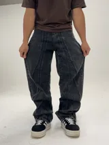 Pantalón de jean negro con efecto lavado, corte amplio tipo baggy y costuras verticales en el frente.