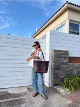Bolso tote de cuero natural color beige, con doble asa de hombro, costuras visibles y cierre de broche.