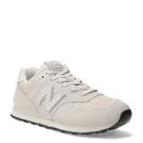 Championes urbanos New Balance modelo 574, color marfil, confeccionados en gamuza y malla con detalles texturizados en la puntera. Presentan el logo N característico en los laterales y suela con diseño moteado.