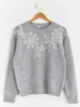Sweater de punto color beige con cuello redondo, manga larga y detalle de bordado floral en la parte superior del pecho.