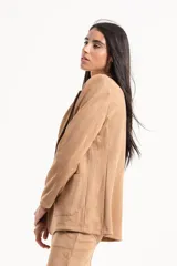 Blazer de gamuza con solapas clásicas, cierre frontal de doble botón y bolsillos laterales. Presenta un corte estructurado con hombreras.