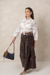 Pollera larga de pana color chocolate, con diseño de tablas frontales y bordados florales en toda la superficie. Cuenta con cintura con pasacintos.