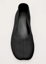 Zapato plano tipo chatita, de color negro, confeccionado en piel de ovino con diseño minimalista y puntera cuadrada.