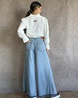Pantalón de jean azul de tiro medio, con corte wide leg y ruedo deshilachado.