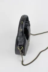 Cartera mini hobo estructurada de cuero negro, decorada con arandelas metálicas doradas en toda la superficie. Cuenta con asa corta de mano y correa de cadena metálica extraíble.