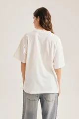 Remera oversize de algodón color blanco, con cuello redondo, mangas cortas y estampa gráfica frontal en blanco y negro con diseño vintage.