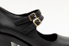 Guillerminas de cuero charol negro con punta cuadrada, taco ancho y correa sobre el empeine con doble hebilla dorada.