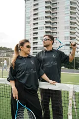 Camiseta de fútbol estilo boxy de manga corta y cuello polo, en color negro con sutiles rayas verticales. Presenta inscripciones estampadas y escudo bordado en el pecho.