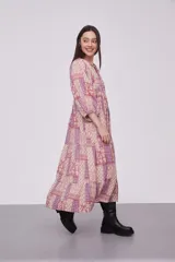 Vestido midi de viscosa con estampado patchwork en tonos rosados y violetas. Presenta cuello redondo con cordones ajustables, mangas 3/4 abullonadas y diseño holgado con falda de volados.