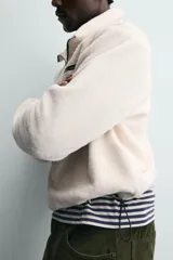 Sudadera de tejido polar con textura efecto pelo, corte relajado, cuello subido con cierre frontal de cremallera, manga larga con puños elásticos y bolsillo con cierre en el pecho.
