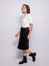 Falda midi de jean color negro, con diseño de cinco bolsillos, cierre frontal con botón metálico y abertura central en el bajo.