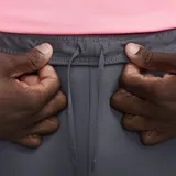 Pantalón de entrenamiento Nike Strike color gris con logo rosado, de corte slim, ligero y transpirable. Cuenta con tecnología Dri-FIT, bolsillos laterales con cierre, pretina elástica con cordón y puños con cierre.