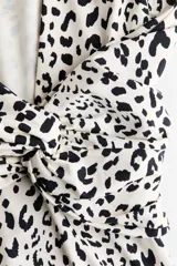 Vestido midi entallado de punto con estampado de leopardo, cuello redondo, manga larga y espalda descubierta con detalle cruzado en la cintura.