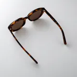 Lentes de sol con armazón ovalado de policarbonato en color negro brillante y cristales oscuros con protección UV400.