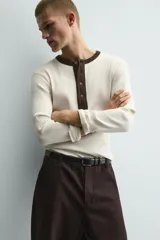 Camiseta de manga larga en tejido de punto canalé color crudo, con cuello redondo y tapeta frontal con botones en color marrón oscuro a contraste.