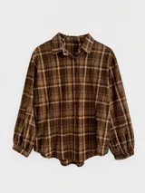 Camisa de manga larga con diseño de cuadros en tonos marrones y beige. Presenta cuello clásico, cierre frontal con botones y mangas con puños fruncidos.