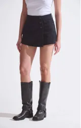 Short pollera de denim negro lavado, con cierre frontal con botones.