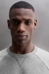 Camiseta de algodón gris de corte relajado con mangas largas ranglán de color gris más claro y puños elásticos. Presenta un pequeño bordado en el pecho y un parche con logo en la parte inferior delantera.