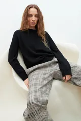 Sweater negro de tejido liso, cuello redondo y manga larga, con puños y ruedo acanalados.