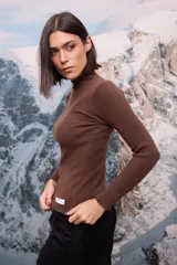 Polera de tejido de punto fino color blanco, con cuello alto, mangas largas y terminaciones con detalle de ondas en puños, cuello y ruedo.