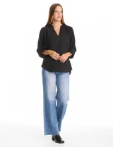 Blusa de corte holgado con escote en V y cuello mao. Presenta mangas largas con sistema de ajuste mediante presilla y botón, permitiendo regular su largo. Confeccionada en tejido con textura sutil.