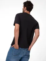 Remera negra de jersey con cuello redondo y mangas cortas. Presenta el logotipo de Caterpillar impreso en el pecho en tono oscuro.