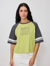 Remera bicolor de ajuste holgado, con cuerpo en tono verde lima y mangas ranglán grises que cuentan con detalles de rayas blancas en los puños. Presenta un estampado frontal con la inscripción "RUSTY 85".
