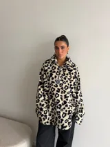 Buzo de peluche con estampado animal print, cuello alto con cierre frontal parcial y detalle de etiqueta decorativa en el pecho.