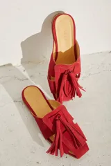 Zueco plano de cuero color dorado, con diseño de tiras anchas entrelazadas en el empeine y punta cuadrada.